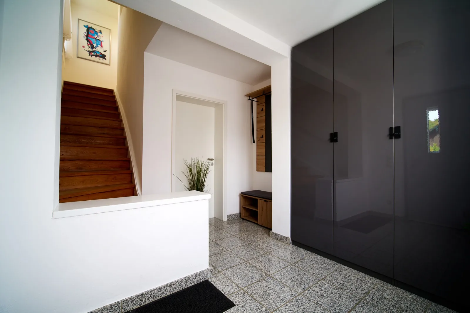 Eingangsbereich mit Garderobe, Sitzbank, Vorratsschrank und Treppe zur Wohnung